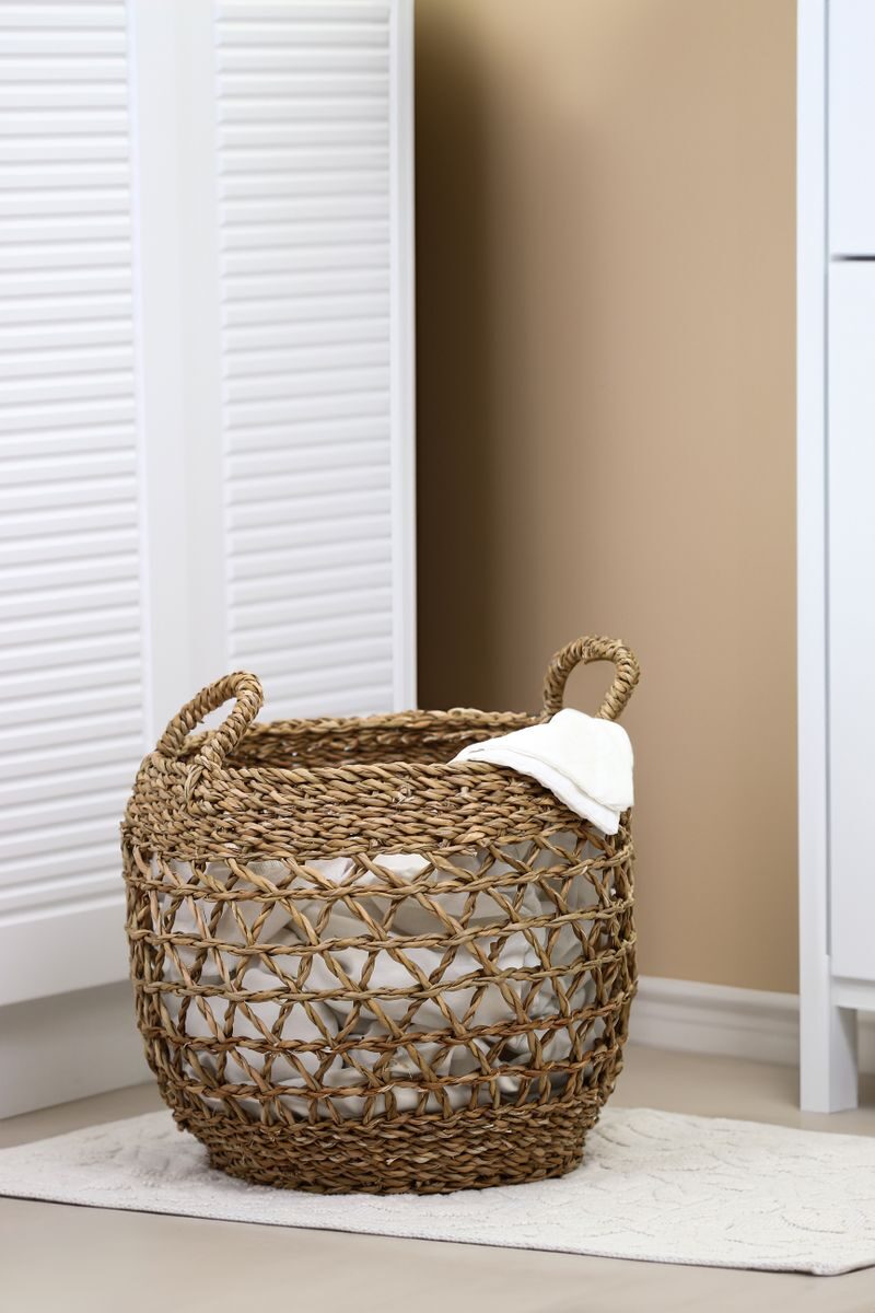 Photo by Kader D. Kahraman Woven laundry basket placed in a modern, minimalist interior setting, perfect for home organization.
