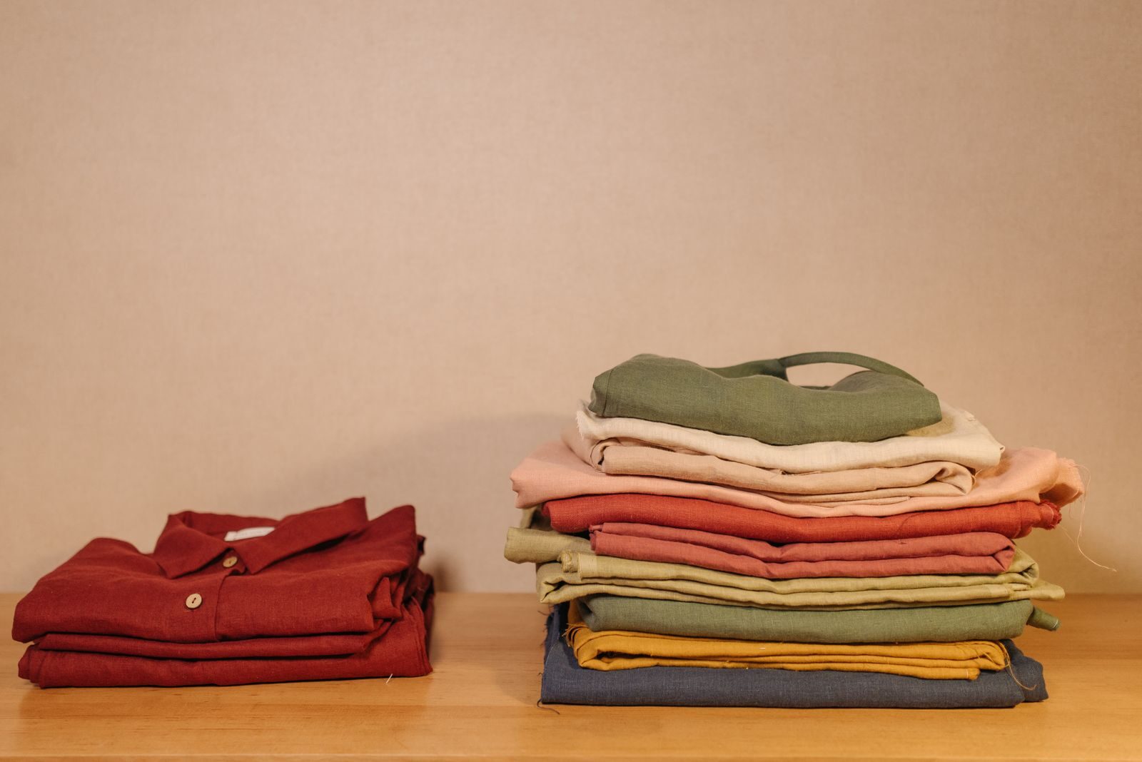 Photo by Pavel Danilyuk Neatly folded colorful clothes on a wooden table, showcasing texture and style.