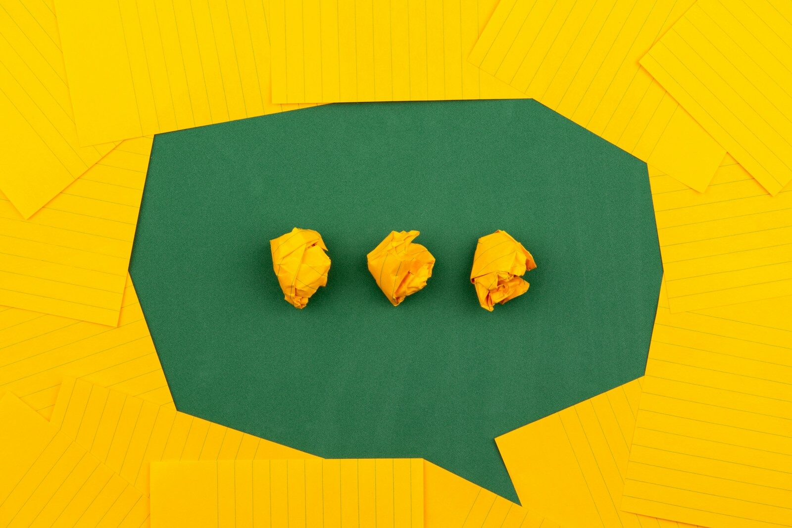 Photo by Volodymyr Hryshchenko three crumpled yellow papers on green surface surrounded by yellow lined papers